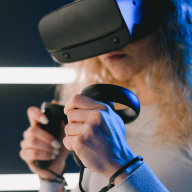 Young woman in virtual reality glasses with controllers in hands